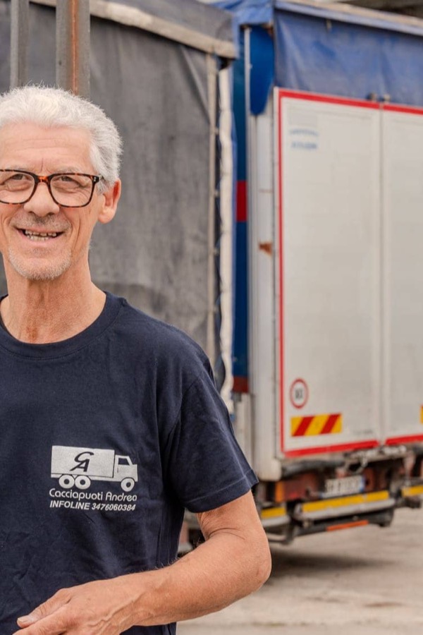 Un operatore dell'impresa accanto al camion, in maglietta aziendale